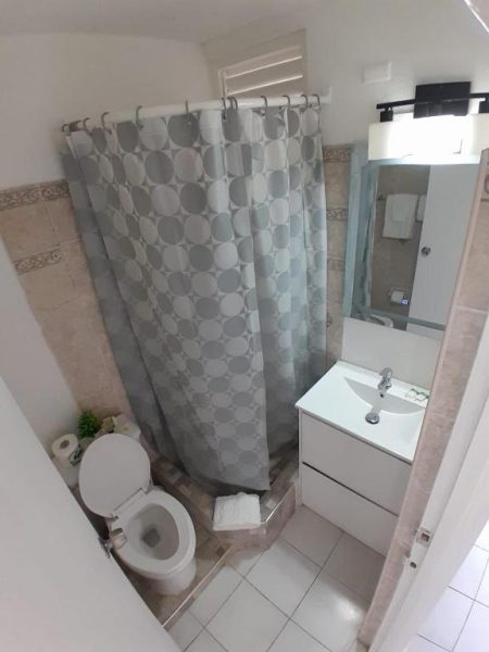 Baño completo con ducha, inodoro y lavabo blanco moderno en Beach Studio 21