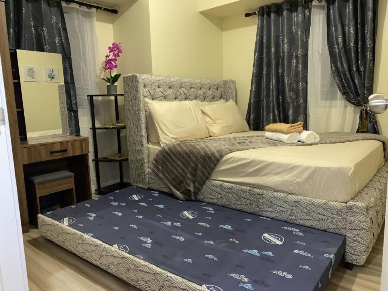 Habitación con cama doble y cama supletoria en apartamento Avida Riala IT Park Cebu