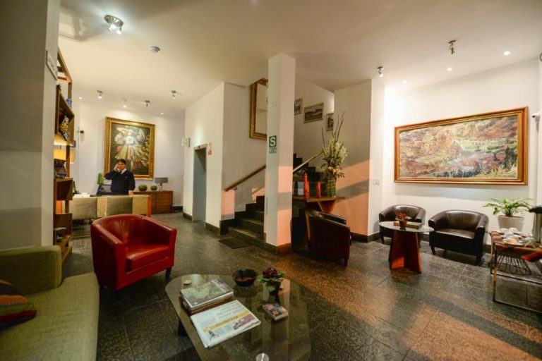 Lobby y recepción elegante del Hotel Plaza de Armas Cusco con pinturas coloniales y zona de descanso