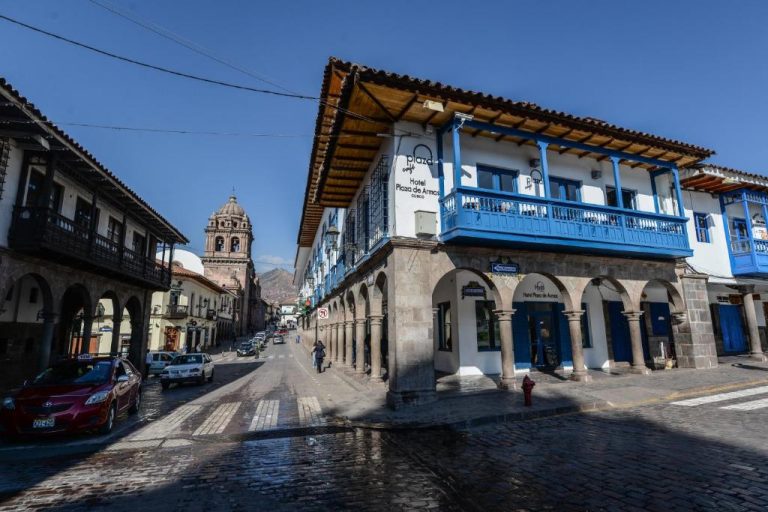 Fachada exterior del Hotel Plaza de Armas Cusco con balcones azules y arcos de piedra colonial