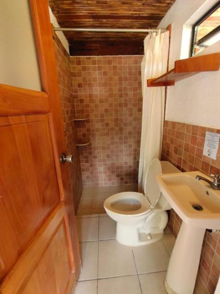 Baño completo con ducha de azulejos, inodoro y lavabo del hotel Coco Bay