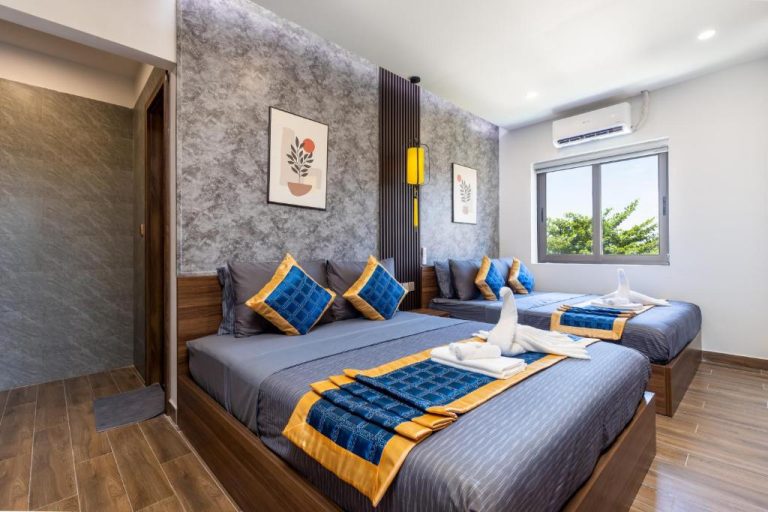 Habitación triple con camas dobles y decoración azul y dorada en Hai Hội Villa Hoi An