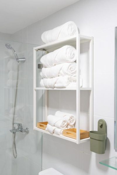 Baño con estantería de toallas blancas y ducha en el hotel Landa Mar Boca Chica