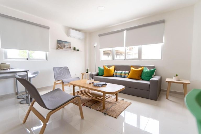 Salón moderno con sofá gris y cojines de colores en apartamento del Landa Mar Boca Chica
