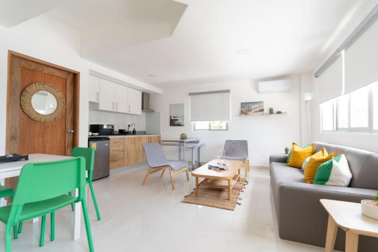 Sala de estar con sofá y cocina americana integrada en el apartamento de Landa Mar Boca Chica