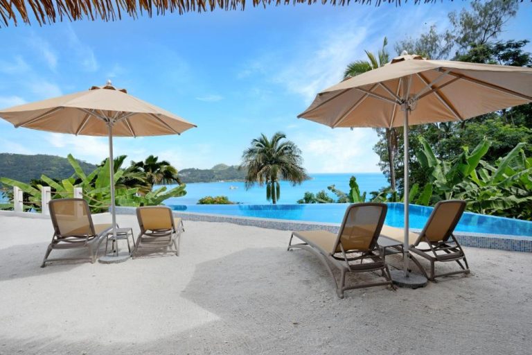 Piscina infinita con tumbonas y sombrillas con vistas al mar en The Bay Seychelles Boutique Hotel