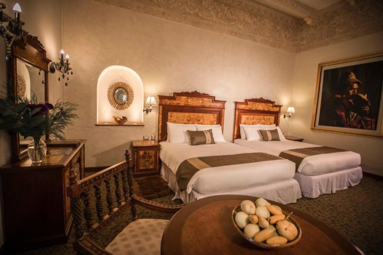 Habitación twin clásica con cabeceros de madera tallada y decoración colonial en Aranwa Cusco Boutique Hotel
