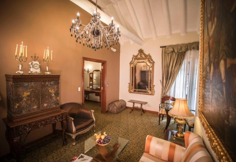 Elegante salón colonial con araña de cristal y antigüedades del Aranwa Cusco Boutique Hotel