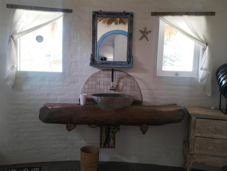 Baño rústico con lavabo de piedra sobre tronco de madera natural en Shaya Cottage