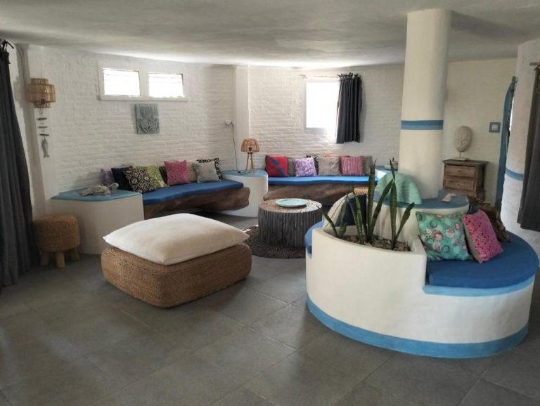 Sala de estar bohemia con sofás azules y cojines de colores en Shaya Cottage