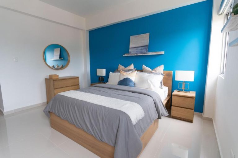 Habitación doble con pared azul y cama king size en Hotel Landa Mar Boca Chica