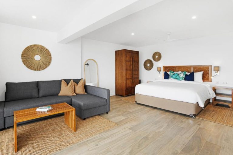 Suite con salón y dormitorio de lujo en The Bay Seychelles Boutique Hotel con decoración tropical