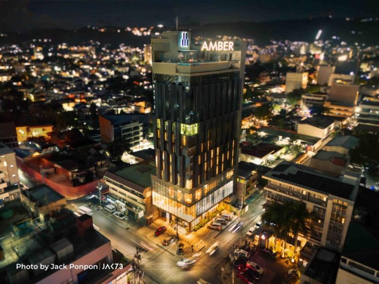 Vista aérea nocturna del Amber Hotel Cebu, moderno rascacielos iluminado en el centro de la ciudad