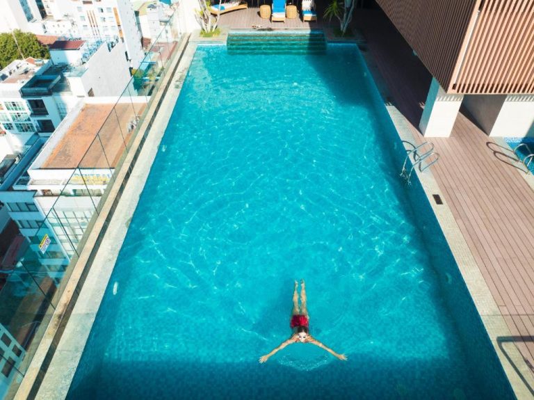Vista aérea de la piscina infinity en la azotea del Gonsala Hotel Nha Trang con bañista
