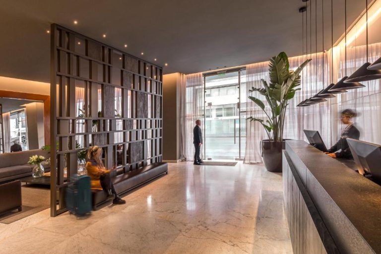Elegante lobby y recepción del Broadway Hotel & Suites con suelo de mármol y decoración moderna