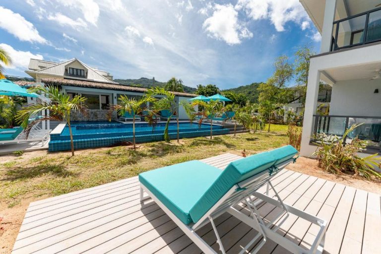 Piscina exterior con tumbonas turquesas y palmeras en Anse La Mouche Villas, Seychelles