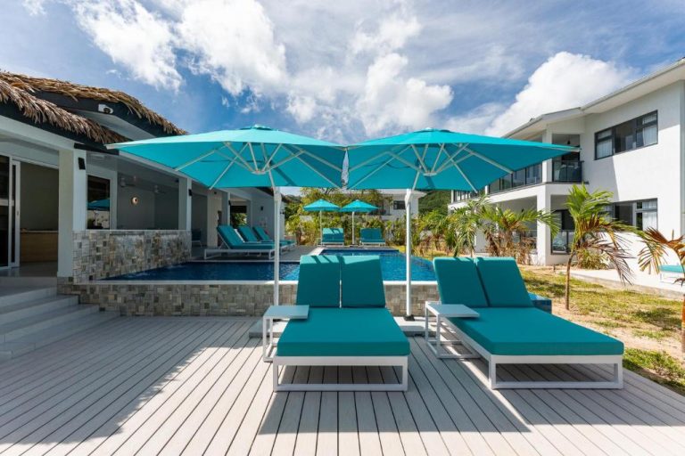Piscina exterior con tumbonas y sombrillas turquesas en Anse La Mouche Villas, Seychelles