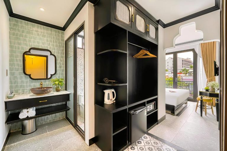 Habitación con baño moderno y armario en Rokas Hoi An Boutique Hotel con balcón y vistas
