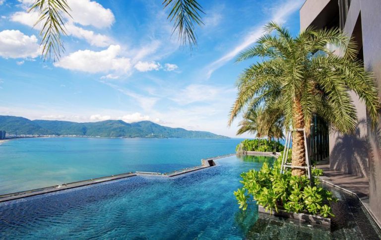 Piscina infinita con vistas al mar y montañas del M Hotel Danang en Vietnam