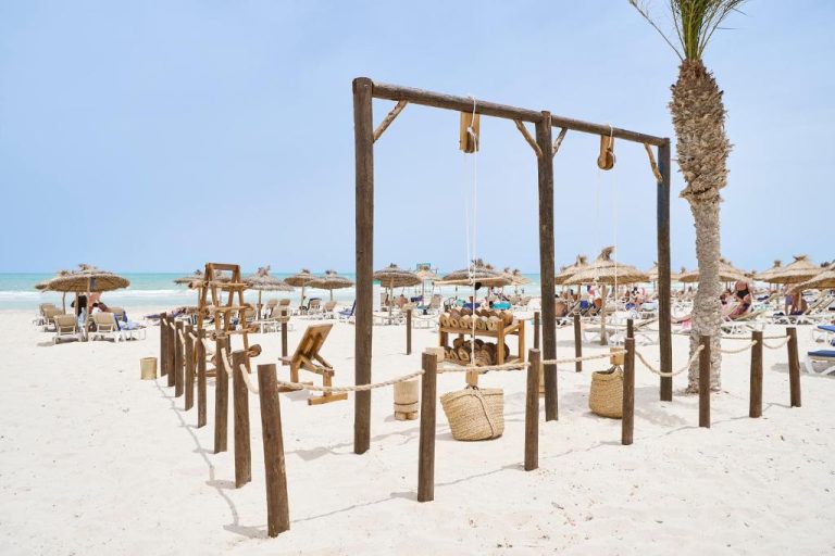 Zona de relax en la playa del Iberostar Waves Mehari Djerba con sombrillas de paja y hamacas