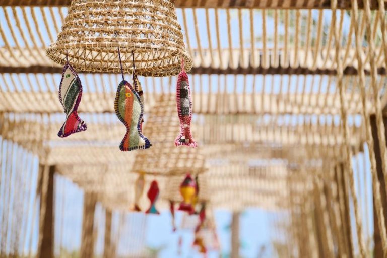 Decoración artesanal con peces de tela colgantes bajo pérgola de mimbre en Iberostar Waves Mehari Djerba