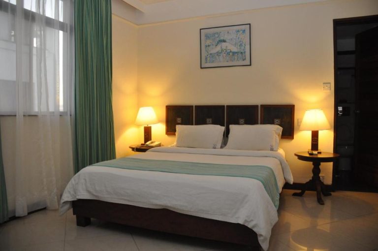 Habitación doble con cama matrimonial y lámparas de mesita en Royal Court Hotel