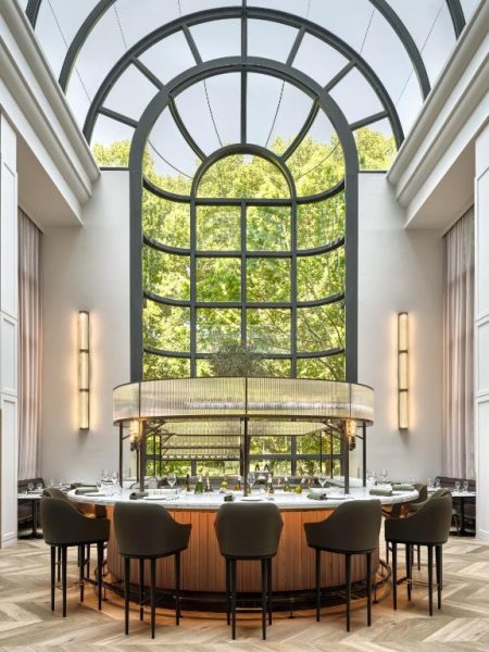 Elegante bar circular con gran ventanal arqueado y vistas a los árboles en Sheraton Grand Sydney Hyde Park