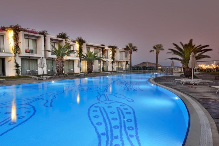 Piscina exterior iluminada al atardecer del Lugga Boutique Hotel & Beach con vistas al mar