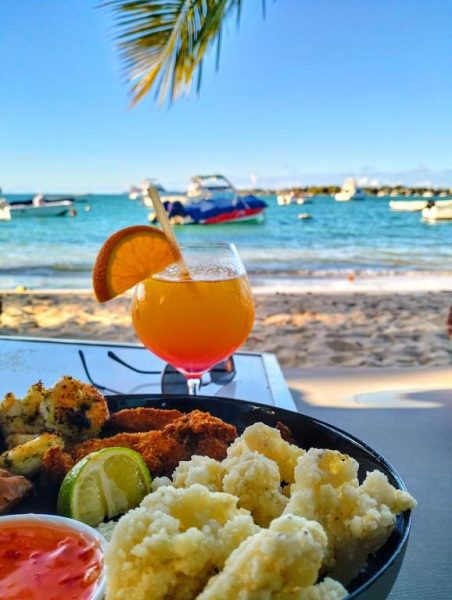 Vista de playa con cóctel tropical y plato de mariscos fritos en Grand Baie Holiday Apartment, Mauricio