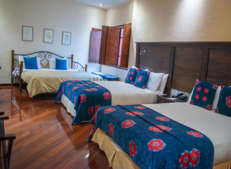 Habitación triple con tres camas y colchas azules florales en La Casona de la Ronda Hotel Boutique