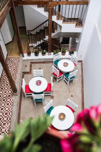 Patio interior con mesas y sillas blancas del Hotel Casa Ecuatreasures Centro Histórico de Quito