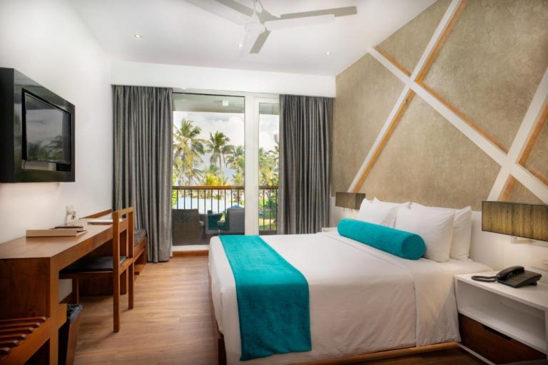 Habitación doble con cama king y balcón con vistas a palmeras en Camelot Beach Hotel