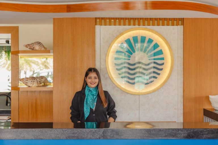 Recepcionista sonriente en el lobby del UMET Seaview Hotel con decoración marinera y logo iluminado