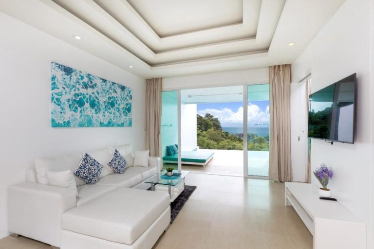 Sala de estar blanca con sofá y vistas al mar en Amala Grand Bleu Resort Hilltops SHA Phuket
