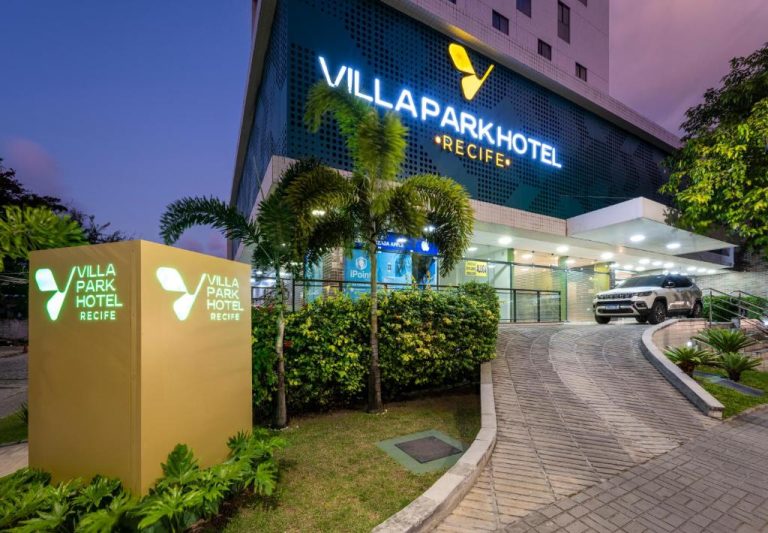 Fachada exterior iluminada del Villa Park Hotel Recife con entrada principal y jardines tropicales