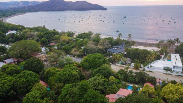 Vista aérea del Villa Del Sol Boutique Hotel rodeado de vegetación tropical frente a la playa con barcos