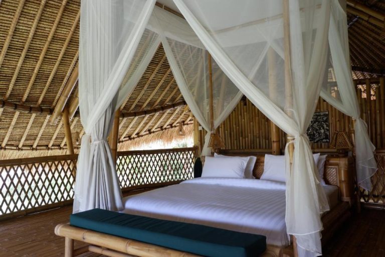 Habitación con cama dosel y mosquitera en Pitu a Punggul Village Escape, cabaña de bambú tropical