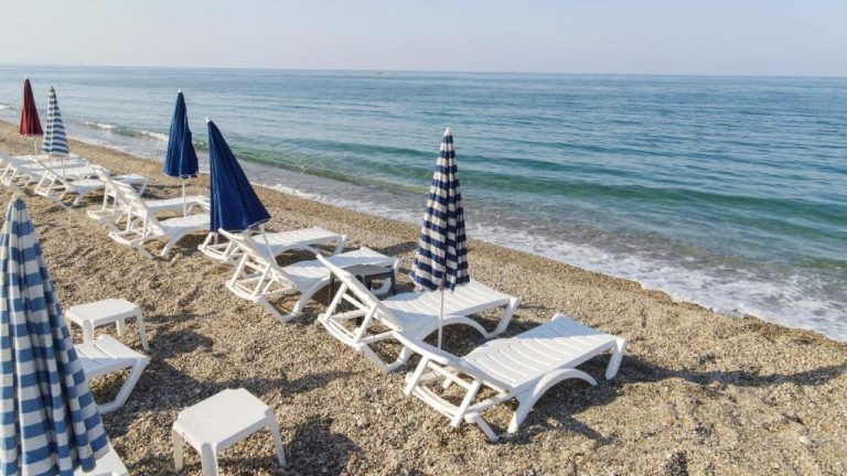 Tumbonas blancas y sombrillas en la playa de piedras del Yalıköy Deniz Otel Istanbul junto al mar