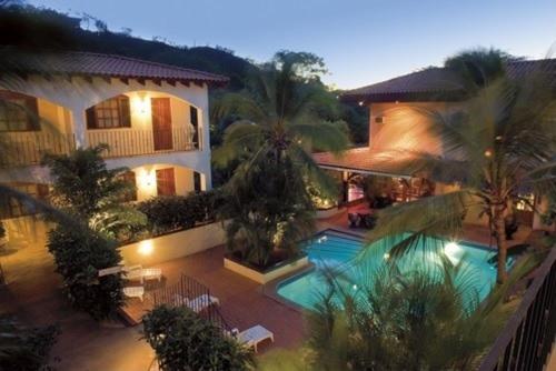 Piscina exterior rodeada de palmeras tropicales en Villa del Sueño al atardecer