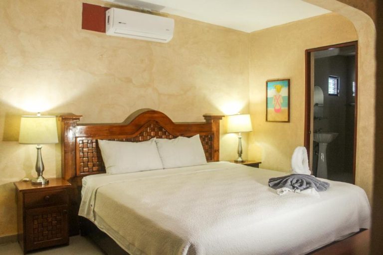 Habitación doble con cama king, cabecero de madera y aire acondicionado en Hotel La Casona Real