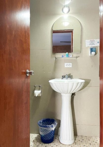 Baño con lavabo de pedestal blanco y espejo en arco del Hotel La Casona Real