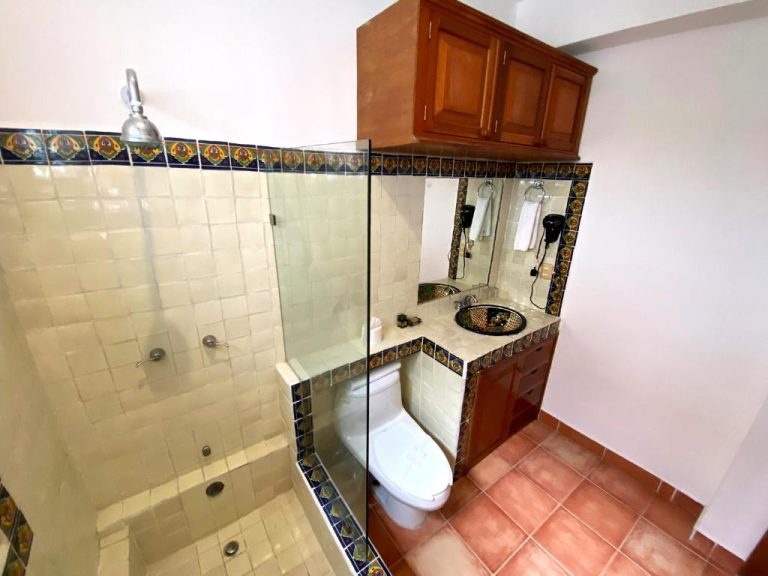 Baño con azulejos de talavera, ducha de cristal y lavabo artesanal en Zihil Ha Hotel
