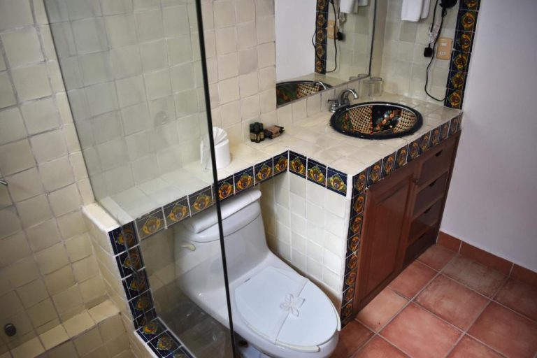 Baño con azulejos de talavera, inodoro, lavabo artesanal y ducha de cristal en Zihil Ha Hotel
