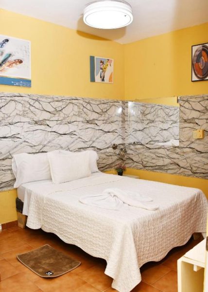 Habitación doble con cabecero de mármol y paredes amarillas en Hotel Mango