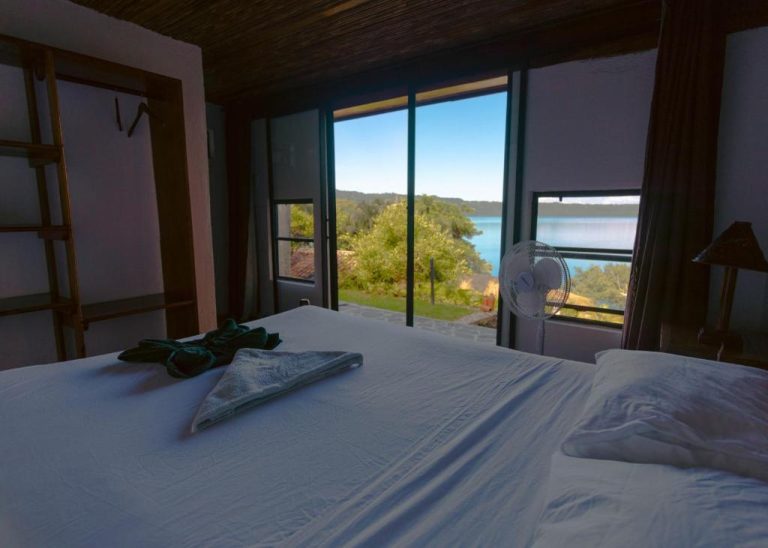Habitación doble con vista al lago y naturaleza en Coco Bay, con cama blanca y ventilador