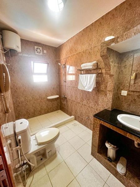 Baño completo con ducha, inodoro y lavabo de mármol en el Riyam Hotel