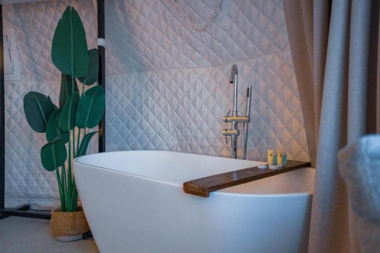Bañera exenta de diseño con grifo plateado y vela en Starry Domes Desert Camp