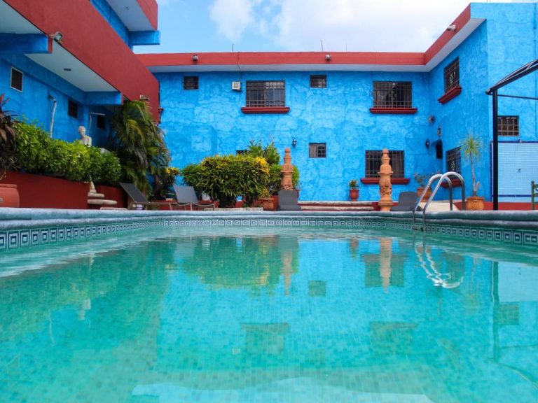 Piscina exterior de aguas cristalinas con fachada azul colonial del Hotel La Casona Real