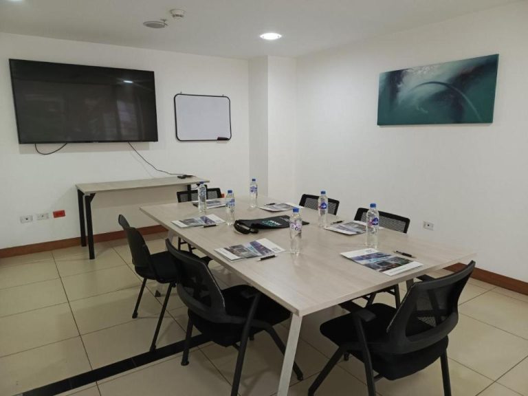 Sala de reuniones con pantalla TV, pizarra blanca y mesa para 8 personas en ZEN Hotel