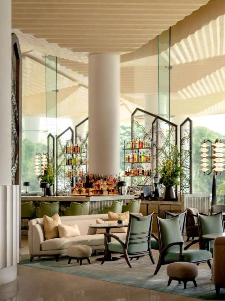 Elegante lobby bar con sillones verdes y barra de cócteles en el hotel Dusit Thani Bangkok